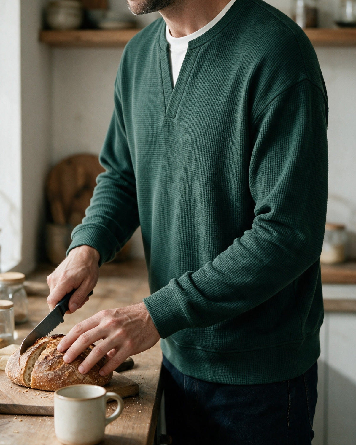 Denholm waffle-knit top in Dark Green, slicing bread in the kitchen